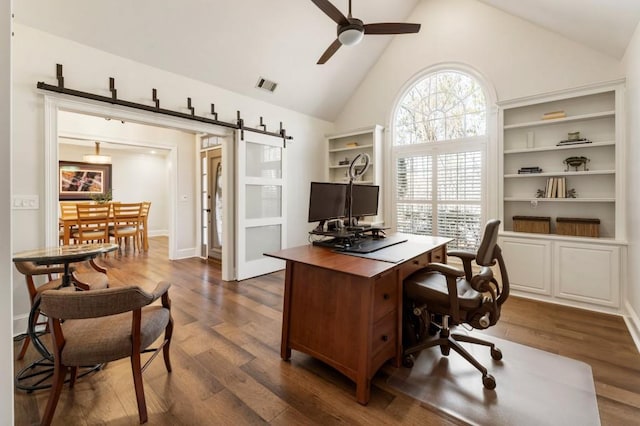 office with dark hardwood / wood-style flooring, high vaulted ceiling, a barn door, and ceiling fan