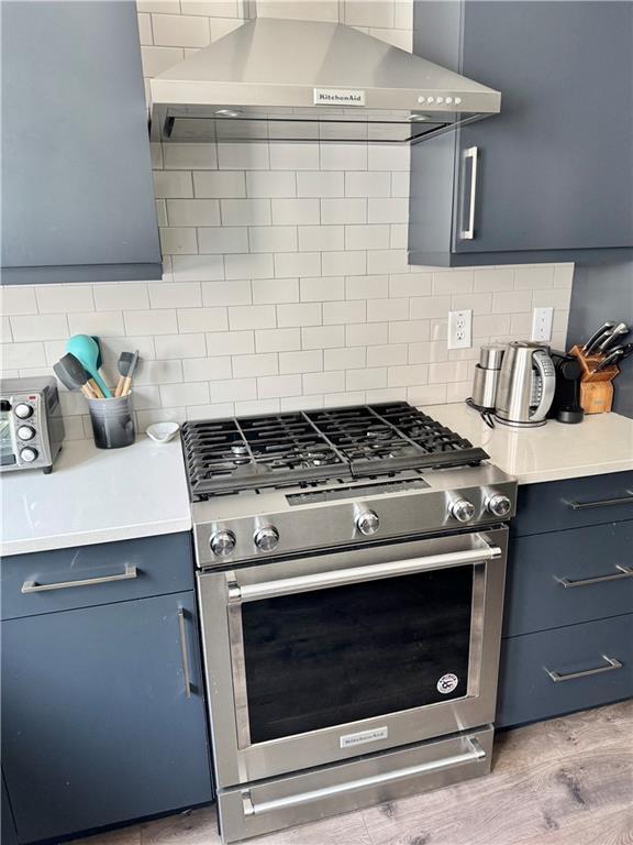 1153 Reynolds Square Ln # 16, Atlanta, GA 30307 - kitchen featuring stainless steel gas stove, wall chimney exhaust hood, light countertops, and backsplash