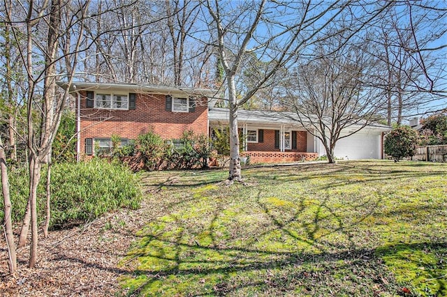 tri-level home featuring a garage, brick siding, and a front yard