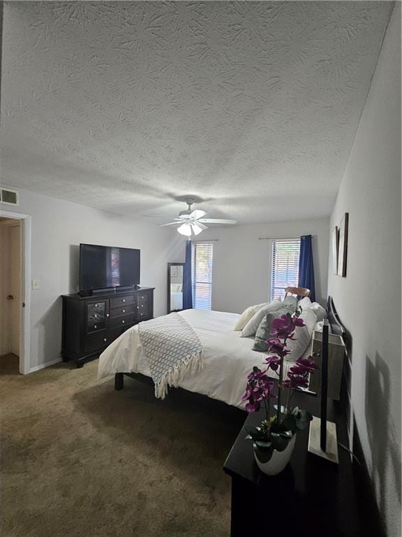 carpeted bedroom with visible vents, a textured ceiling, and a ceiling fan