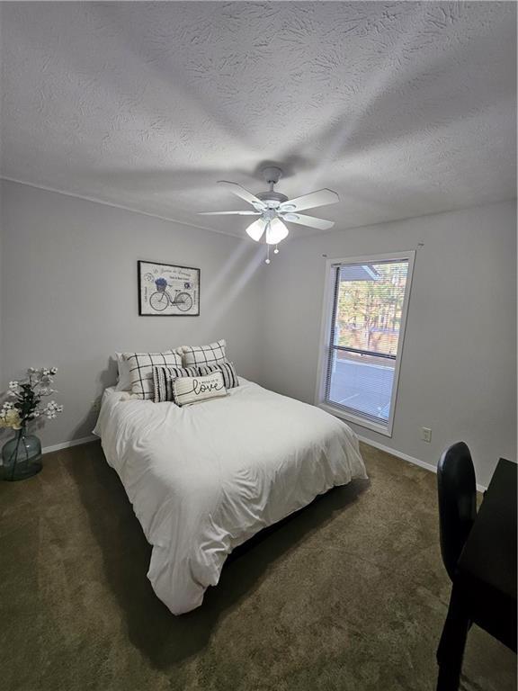 bedroom featuring a ceiling fan, carpet, baseboards, and a textured ceiling