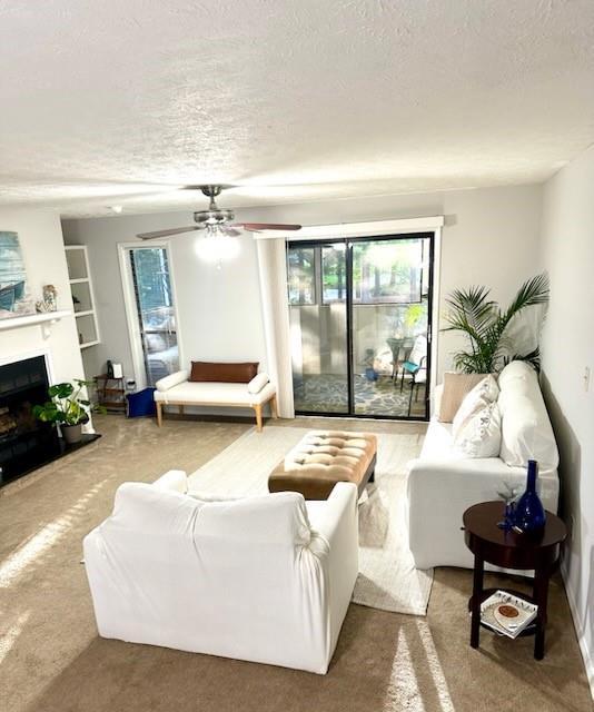 1507 Wynnes Ridge Cir SE, Marietta, GA 30067 - living area with a textured ceiling, a fireplace, ceiling fan, and carpet flooring