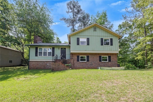 tri-level home with a front lawn, board and batten siding, brick siding, and a chimney