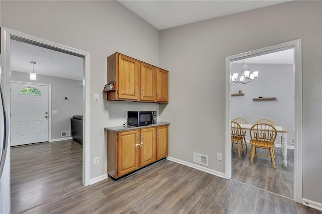 kitchen featuring a chandelier, black microwave, visible vents, and wood finished floors