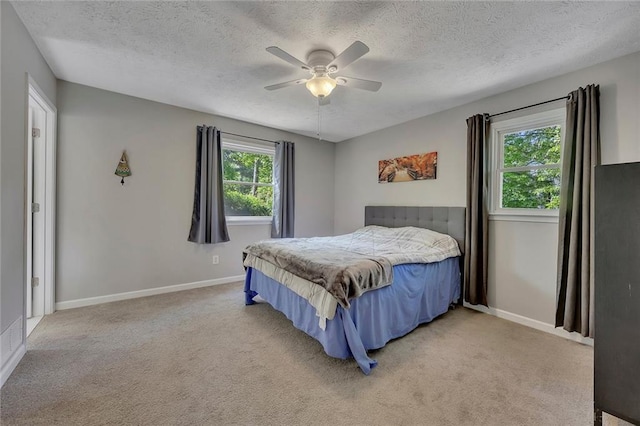 bedroom featuring a textured ceiling, light carpet, and baseboards