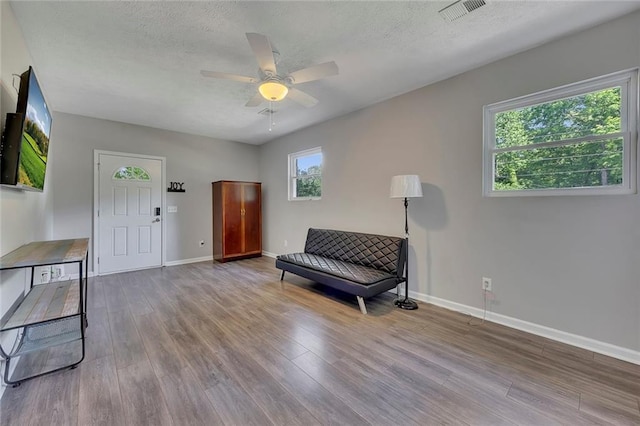 sitting room featuring wood finished floors, a textured ceiling, visible vents, baseboards, and ceiling fan