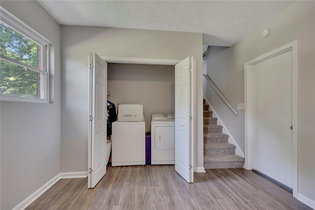laundry room with washing machine and dryer, a textured ceiling, baseboards, wood finished floors, and laundry area