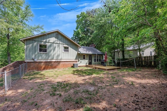 back of property featuring cooling unit, a chimney, a wooden deck, board and batten siding, and a fenced backyard
