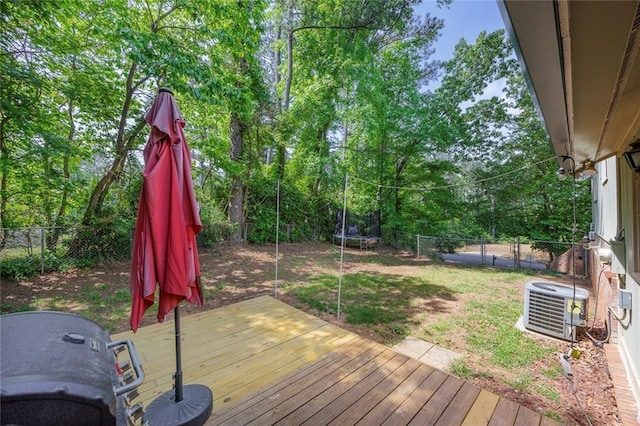 wooden terrace featuring a trampoline, central AC unit, and a fenced backyard