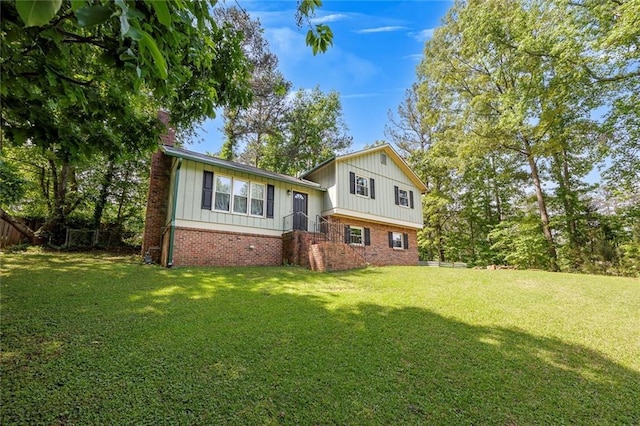 back of property featuring a lawn, board and batten siding, brick siding, and a chimney