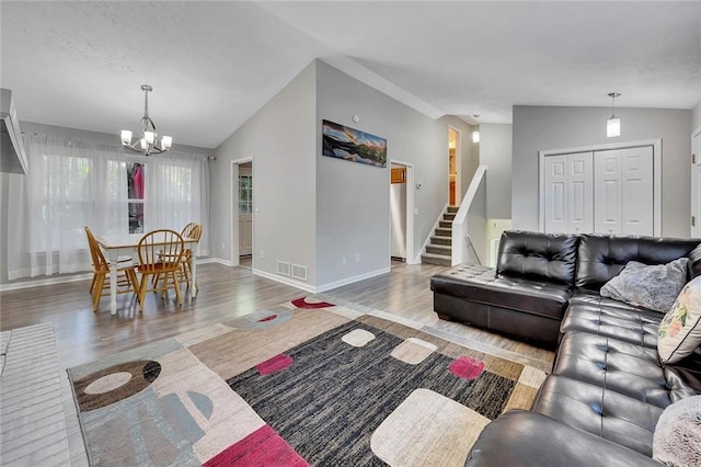living area with stairs, wood finished floors, vaulted ceiling, an inviting chandelier, and baseboards