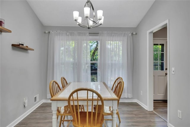 dining space with a chandelier, baseboards, visible vents, and wood finished floors