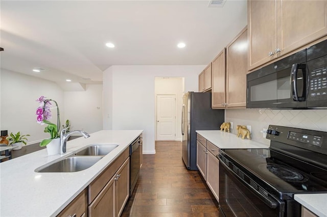 kitchen featuring dark wood-style floors, light countertops, backsplash, a sink, and black appliances