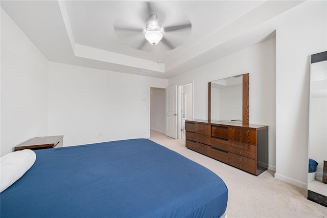 carpeted bedroom with a ceiling fan, a raised ceiling, and baseboards