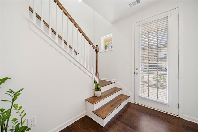 foyer with stairway, baseboards, visible vents, and dark wood-style flooring