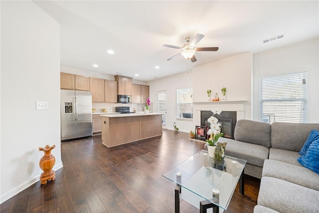 living area with dark wood-style floors, baseboards, visible vents, and a glass covered fireplace