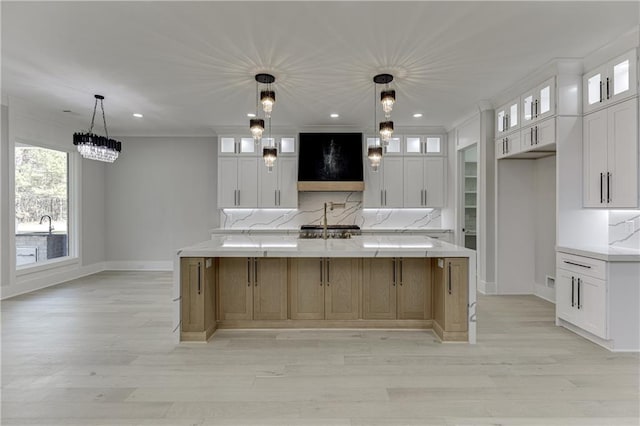 kitchen with decorative light fixtures, tasteful backsplash, white cabinetry, sink, and a large island