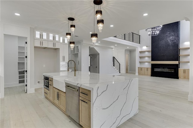 kitchen with a spacious island, sink, an inviting chandelier, appliances with stainless steel finishes, and light stone countertops