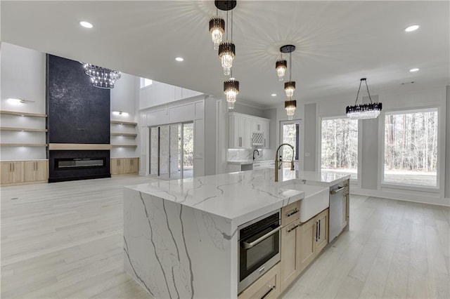 kitchen featuring sink, light stone counters, decorative light fixtures, appliances with stainless steel finishes, and a large island