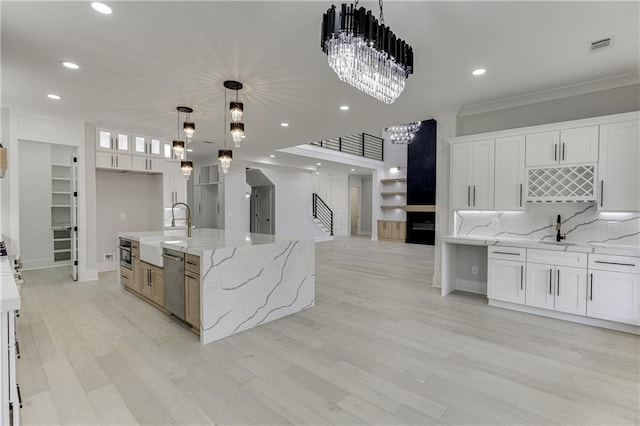 kitchen featuring pendant lighting, appliances with stainless steel finishes, a spacious island, light stone counters, and white cabinets