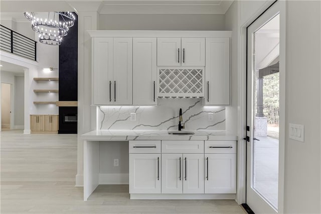 interior space with light stone counters, sink, tasteful backsplash, and white cabinets