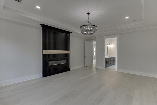 unfurnished living room with a chandelier, ornamental molding, a raised ceiling, and light hardwood / wood-style flooring