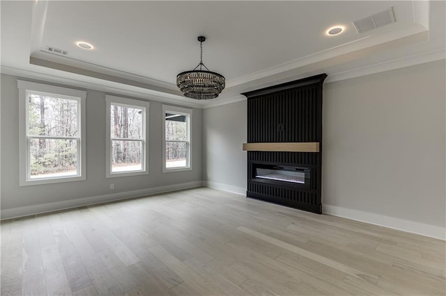 unfurnished living room with crown molding, a raised ceiling, and light hardwood / wood-style flooring