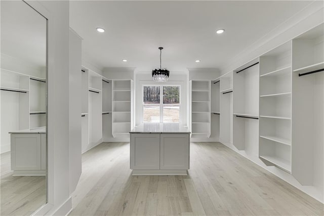 walk in closet with a notable chandelier, a barn door, and light wood-type flooring