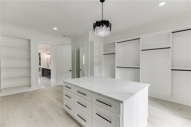 spacious closet with an inviting chandelier and light hardwood / wood-style floors