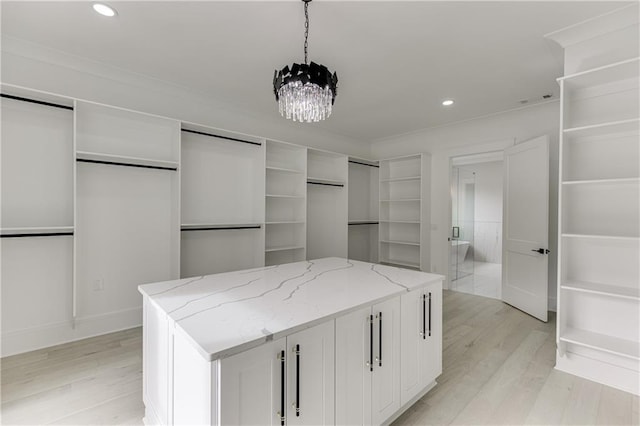 walk in closet with a chandelier and light wood-type flooring