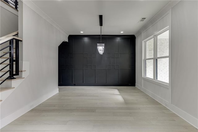 unfurnished dining area with crown molding, light hardwood / wood-style flooring, and a chandelier