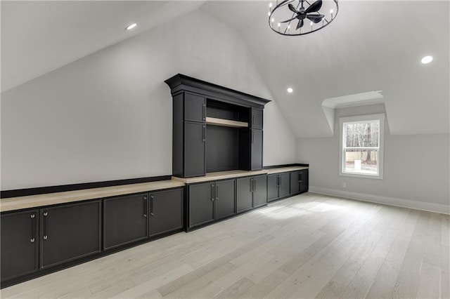 additional living space featuring lofted ceiling, light hardwood / wood-style floors, and a chandelier