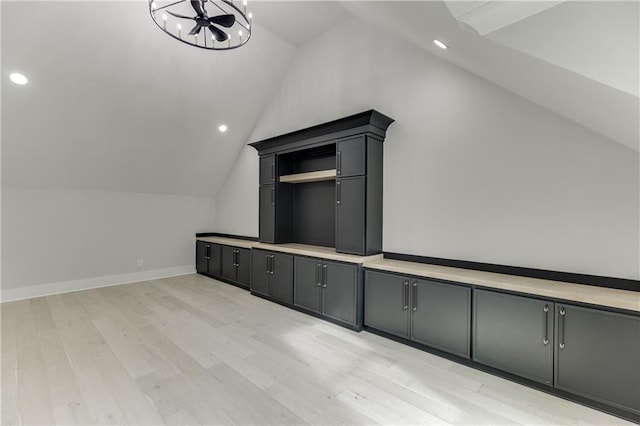 bonus room with a notable chandelier, vaulted ceiling, and light wood-type flooring