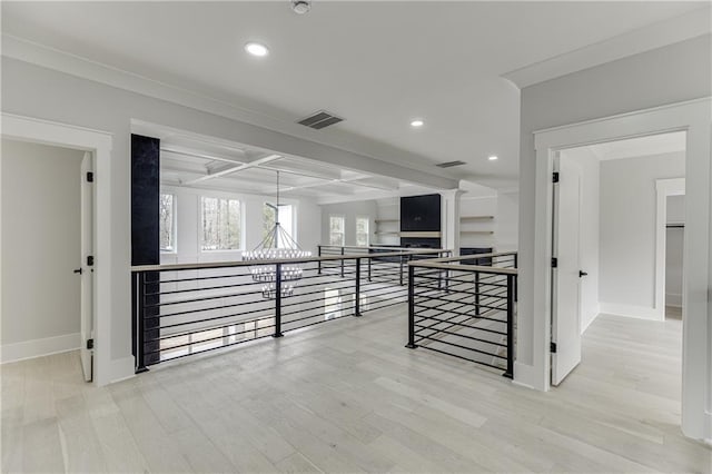 hallway featuring beamed ceiling, coffered ceiling, an inviting chandelier, and light wood-type flooring