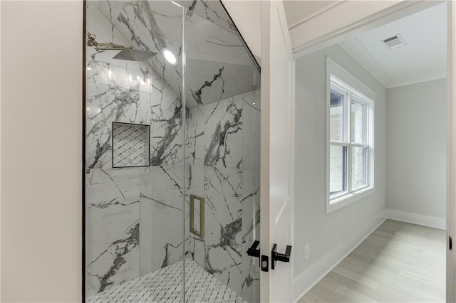 bathroom featuring hardwood / wood-style flooring, a shower with shower door, and ornamental molding