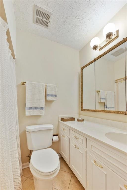 bathroom featuring vanity, toilet, a textured ceiling, and tile patterned flooring