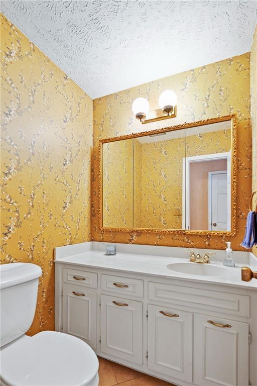 bathroom with vanity, toilet, a textured ceiling, and tile patterned flooring