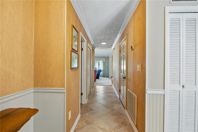 hallway featuring a textured ceiling, light tile patterned floors, and ornamental molding