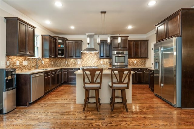 2025 Eagle Rdg, Roswell, GA 30076 - kitchen featuring appliances with stainless steel finishes, wall chimney exhaust hood, dark brown cabinets, a kitchen island, and ornamental molding