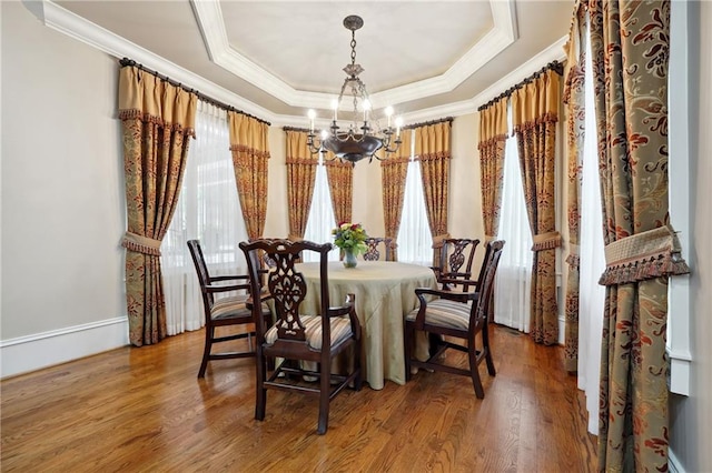 dining space with a healthy amount of sunlight, wood-type flooring, and an inviting chandelier