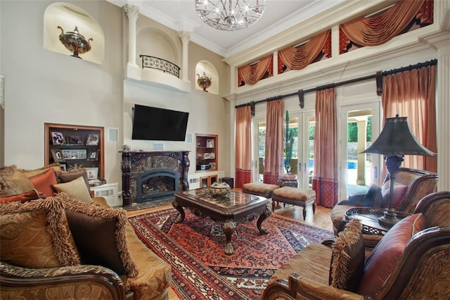 living room with hardwood / wood-style flooring, an inviting chandelier, ornamental molding, and french doors