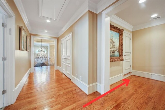 corridor with crown molding, hardwood / wood-style floors, and a notable chandelier