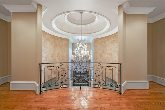 interior space featuring a raised ceiling, hardwood / wood-style floors, a chandelier, and ornamental molding