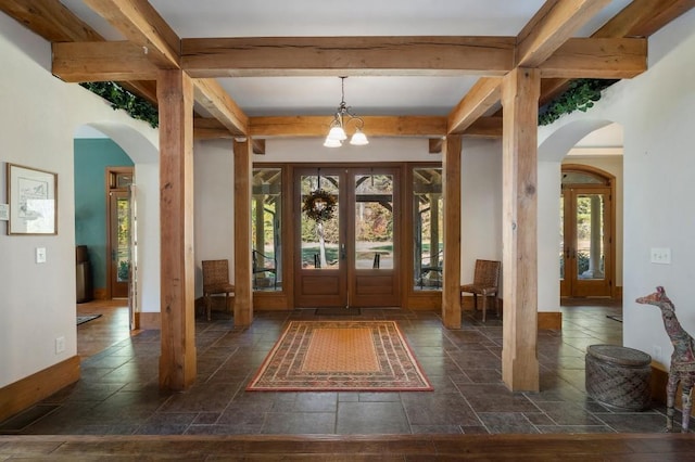 entryway featuring beam ceiling, a chandelier, a healthy amount of sunlight, and french doors