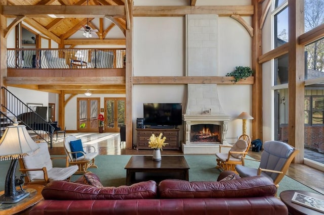 living room with beam ceiling, high vaulted ceiling, a fireplace, and ceiling fan