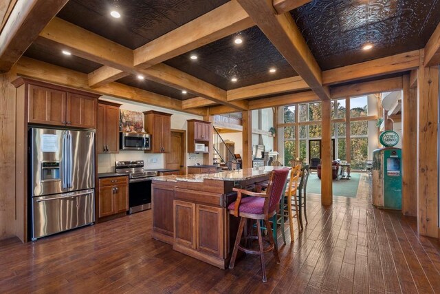 kitchen featuring a breakfast bar area, a kitchen island, appliances with stainless steel finishes, and dark wood-type flooring