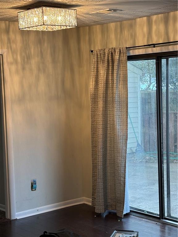 interior space featuring baseboards, a notable chandelier, and dark wood finished floors