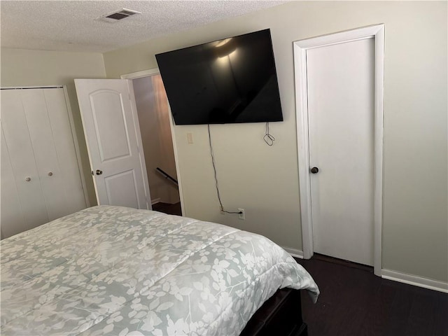 bedroom with visible vents, baseboards, a closet, a textured ceiling, and dark wood-style flooring