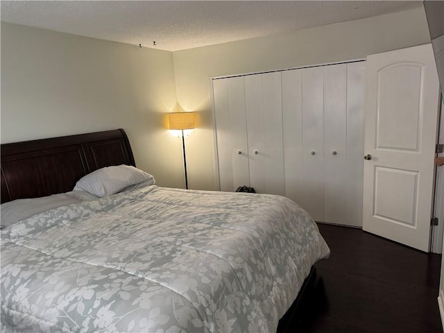 bedroom with dark wood-style floors, a closet, and a textured ceiling