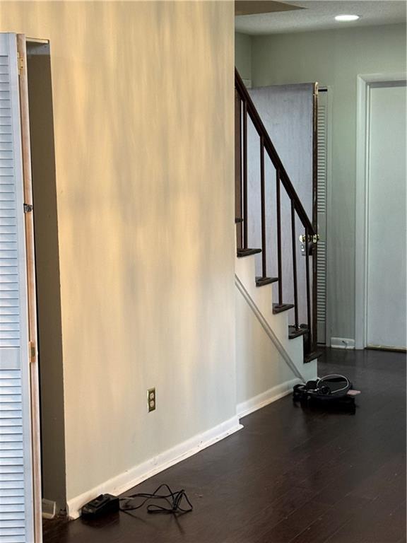 interior space with stairway, dark wood-type flooring, and baseboards